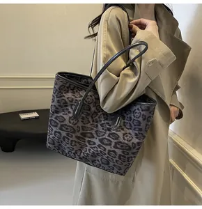 Detailed view of large leopard print tote bag featuring textured fabric and leather handles
