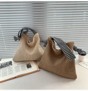 Close-up of straw beach tote bags with houndstock pattern fabric handles on white background