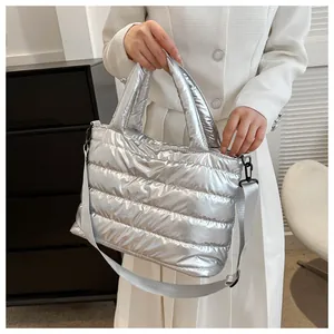 Detail of silver metallic quilted tote bag featuring a glossy finish and long strap
