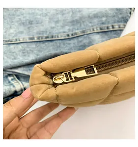 Primer plano de la cremallera dorada y textura acolchada en el neceser de terciopelo camel