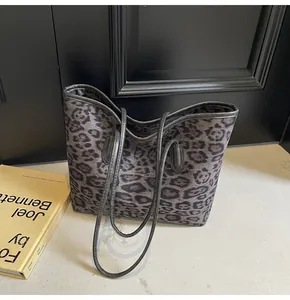 Close-up of leopard print tote bag showing black shoulder straps and zipper closure