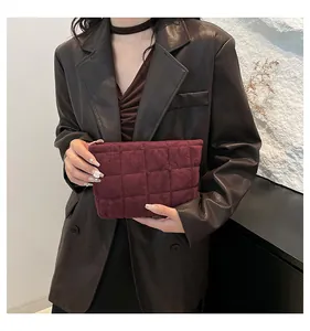 Detalle del neceser de terciopelo acolchado burdeos sostenido por una modelo con estilo
