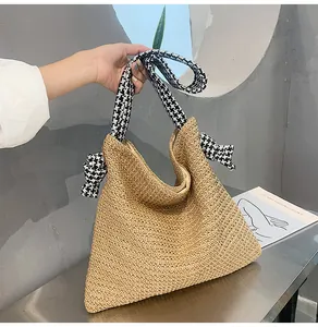 Detail of straw woven hobo bag featuring a stylish houndstooth pattern wide strap