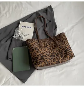 Detail of leopard print tote bag with brown leather handles and reinforced bottom base