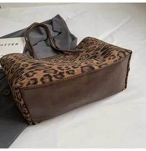 Close-up of leopard print tote bag with brown leather handles and stitching details