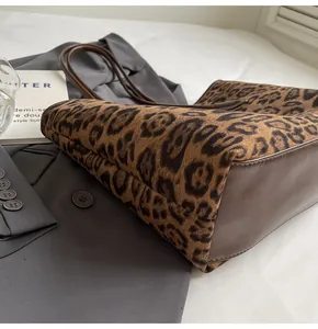Detail of leopard print tote bag with plush texture and leather base on grey suit jacket