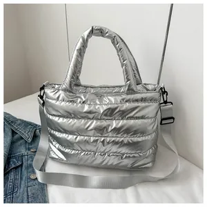 Close-up of shiny silver quilted puffer bag with adjustable wide nylon shoulder strap