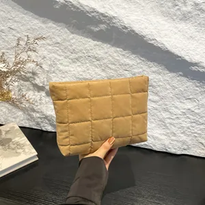 Detalle de una bolsa de maquillaje de terciopelo caqui acolchado con textura suave y elegante