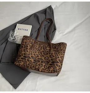 Leopard print tote bag with brown leather handles placed on minimalist office setting