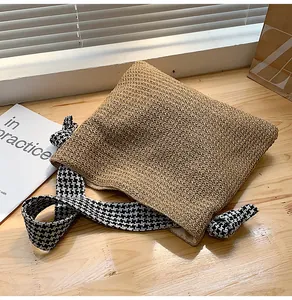 Detailed texture of hand-woven straw bag with stylish houndstooth fabric strap