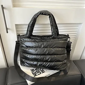 Quilted padded tote bag in glossy black fabric with top handle and shoulder strap