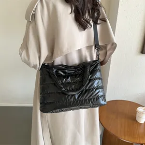 Glossy black quilted padded tote bag for women with crossbody strap and top handles