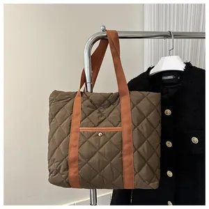 Nahaufnahme der braunen Stepptasche mit orangefarbenen Griffen und Metallschnalle