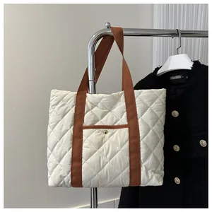 Detailansicht einer cremefarbenen Stepptasche mit braunen Gurten an einem Metallkleiderbügel