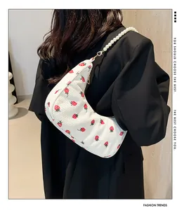 Detail of white corduroy crescent hobo bag with strawberry print and pearl chain strap