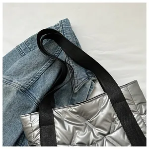 Schicke gesteppte Tragetasche in Silber mit schwarzem Nylonriemen auf einer Jeansjacke