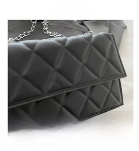 Detail of black quilted leather shoulder bag featuring classic diamond pattern and chain