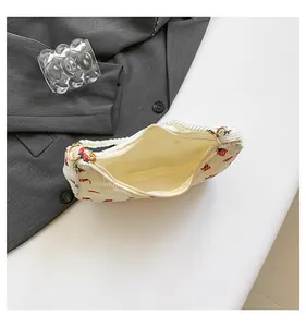 Detail of corduroy crescent bag with strawberry print and elegant pearl strap handle