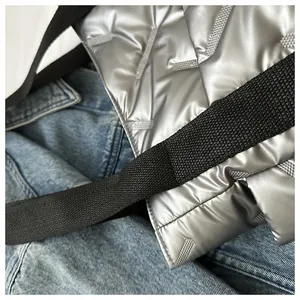 Detail der silbernen gesteppten Tragetasche mit Punkt-K-Muster und schwarzem Schultergurt