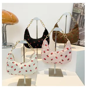 Detail of four corduroy hobo bags with strawberry prints and golden chain handles