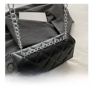 Detail of classic black quilted pattern with metallic silver chain strap on crossbody bag