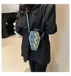 Detail of coffin-shaped crossbody bag with blue snake skin texture and metal rivets