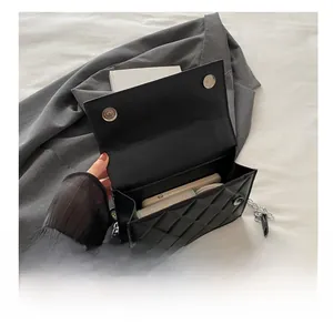 Detail showing internal capacity of black quilted chain bag with phone and makeup items