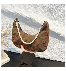 Close-up of brown corduroy crescent bag featuring strawberry prints and pearl chain strap