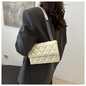 Quilted beige shoulder bag with silver chain strap worn by model in grey blazer jacket