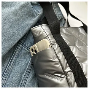 Detail der silbernen Stepptasche mit Seitentasche und Smartphone zum Größenvergleich