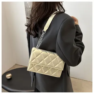Detailed view of beige quilted handbag with elegant silver chain strap on a shoulder