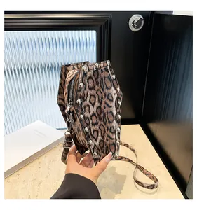 Detail of leopard print coffin crossbody bag with silver rivets and metallic zipper closure