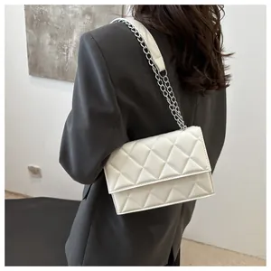 Detail of white quilted rhombus pattern bag with silver chain strap on model