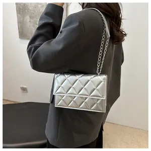 Detail view of silver quilted chain bag worn over the shoulder with a grey blazer