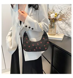 Detail of black corduroy crescent bag with strawberry print and gold chain strap