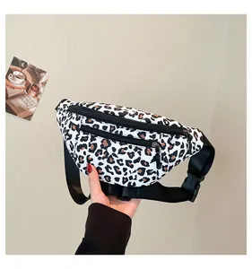 Detail of leopard print nylon waist bag featuring dual black zippers and adjustable strap