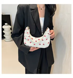 Close-up of cream corduroy hobo bag with red strawberry prints and pearl chain detail
