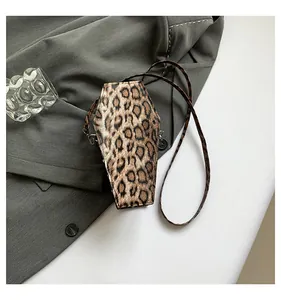 Detailed view of leopard print coffin-shaped crossbody bag on a grey blazer fabric