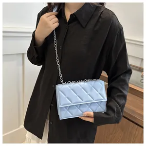 Close-up of quilted light blue shoulder bag with silver chain strap worn by a model