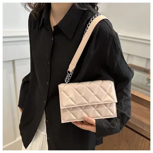 Detail of beige quilted rhombic shoulder bag with silver metal chain on female model