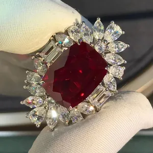 Luxurious 10ct red ruby ring with marquise halo on silver band held in gloved hand