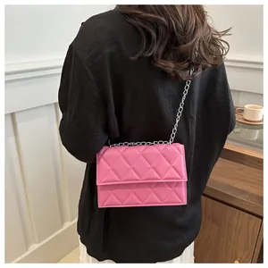 Detail shot of pink quilted crossbody bag with silver chain strap worn by a model
