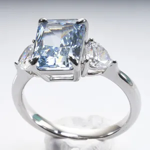 Close-up of radiant cut light blue stone with pear side diamonds in silver 4-prong setting