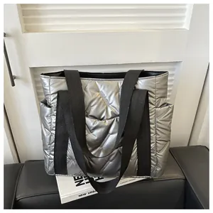 Detail der silbernen gesteppten Daunen-Tote-Bag mit schwarzen Trägern auf Sofa