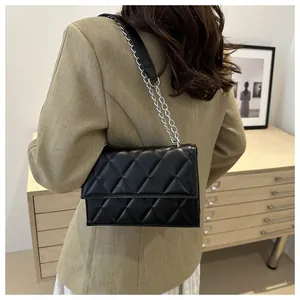 Modern black quilted crossbody bag with silver chain strap shown on a model's shoulder