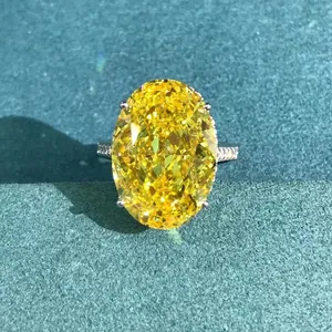 Macro detail of oval cut yellow gemstone ring with pavé diamond band on teal surface