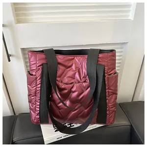 Detailansicht der burgunderroten Puffer-Tasche mit Steppmuster und glänzender Optik