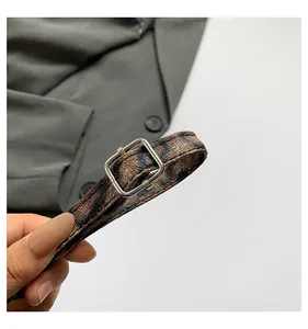 Detail of leopard print PU leather strap with polished silver metal buckle on a dark background