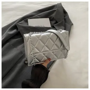 Detail of silver quilted crossbody bag with metal chain strap and luxury texture