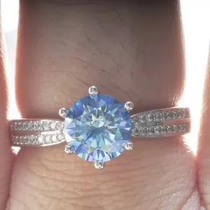Macro view of blue moissanite sterling silver ring with six-prong setting on finger